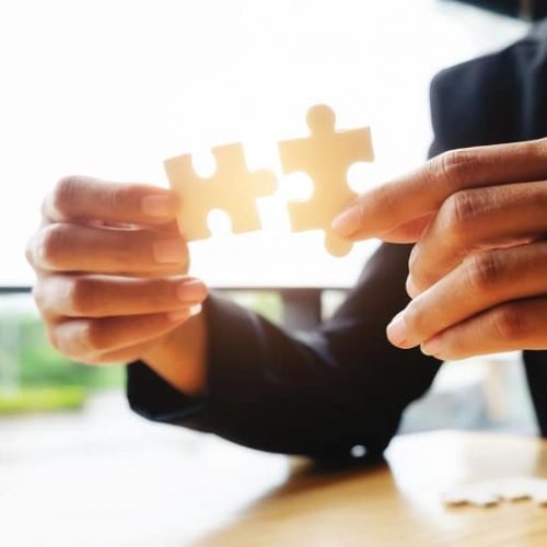 Businessman hands connecting jigsaw puzzle. Business solutions, success and strategy, learning concept. Close up photo with small dof